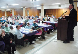 Catholics from central and southern Indiana fill Priori Hall at Our Lady of the Most Holy Rosary Parish in Indianapolis on March 30 to listen to Guy Gruters, right, tell his story of how his faith in God helped him endure nearly six years of confinement as a prisoner of war in North Vietnam. (Photo by Sean Gallagher)