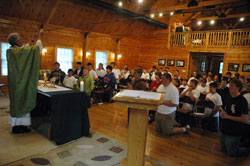 Father Thomas Kovatch, pastor of St. Teresa Benedicta of the Cross Parish in Bright, elevates the Body and Blood of Christ during a June 15 Mass as part of Bishop Bruté Days, an annual vocations retreat and camping experience for junior high and high school-aged youths sponsored by Bishop Simon Bruté College Seminary in Indianapolis. It was held from June 14-17 at the Indiana Future Farmers of America Leadership Center in southern Johnson County, and attracted more than 40 participants from across the archdiocese and beyond. (Photo by Sean Gallagher)