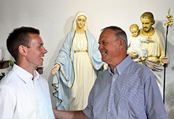 The journey of Mike Waters, left, into the Catholic Church received a substantial boost from William Ritz after an unexpected encounter in an exercise facility. Here, the two friends talk after morning Mass on July 30 inside Holy Family Church in Richmond. (Photo by John Shaughnessy)