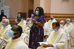 Dabrice Bartet, a member of St. Monica Parish in Indianapolis, carries an urn containing chrism oil during the June 29 celebration of the annual archdiocesan chrism Mass at SS. Peter and Paul Cathedral in Indianapolis. (Photo by Sean Gallagher)