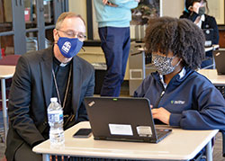 Providence Cristo Rey sophomore Juniya Hughes shows Archbishop Charles C. Thompson a presentation she is working on for a class. The archbishop visited the Indianapolis private Catholic high school on Feb. 23. (Photo by Natalie Hoefer)