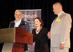 As abortion survivor Gianna Jessen delivers her talk at the Right to Life of Indianapolis fundraising dinner on Sept. 28, she is supported by David Liebel, left, and David Certo. She asked the two members of the audience for their support as a precaution against falling because she has cerebral palsy. (Photo by John Shaughnessy)